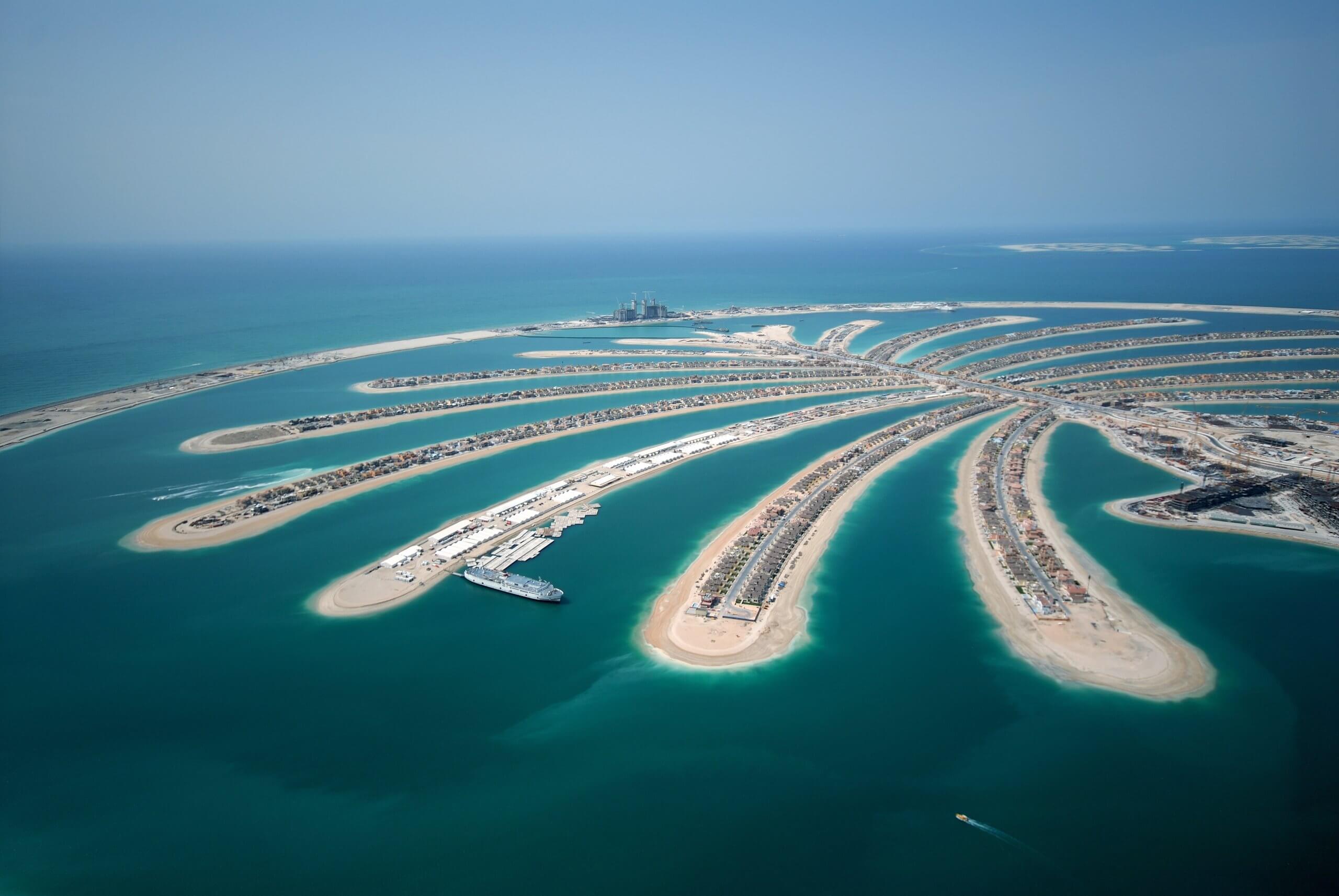 "Aerial view of The Palm Jumeirah artificial archipelago in Dubai, representing a giant palm stretching out into the Persian Gulf, with landscaped islets and waterfront buildings.